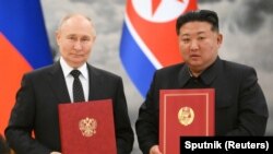 俄罗斯总统普京与朝鲜领导人金正恩在平壤举行的签字仪式上合影。（2024年6月19日）