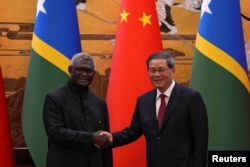 中国总理李强与所罗门群岛总理索加瓦雷在一个签字仪式后握手。（2023年7月10日）