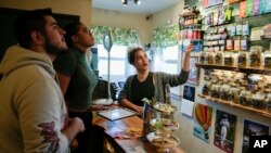 Твайла Бессі, праворуч, допомагає клієнтам купувати марихуану в Home Grown Apothecary, 19 квітня 2024 року в Портленді, штат Орегон.