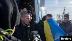 Swapped Ukrainian prisoners of war disembark from a bus after a prisoner exchange for Russian POWs, at an unidentified location in Ukraine, Jan. 31, 2024. (Ukrainian Presidential Press Service/Handout via Reuters)
