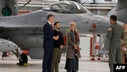 Президент України Володимир Зеленський (в середині) з бельгійським прем’єр-міністром Александром Де Кроо (ліворуч) з міністеркою оборони Бельгії Людивін Дедондер біля літака F-16. 30 таких літаків Бельгія зобов’язалася надати Україні.