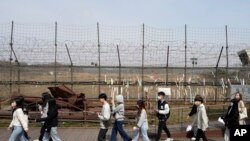 资料照片:2023年3月24日，人们经过靠近朝鲜边境的韩国坡州市临津阁的铁丝网。