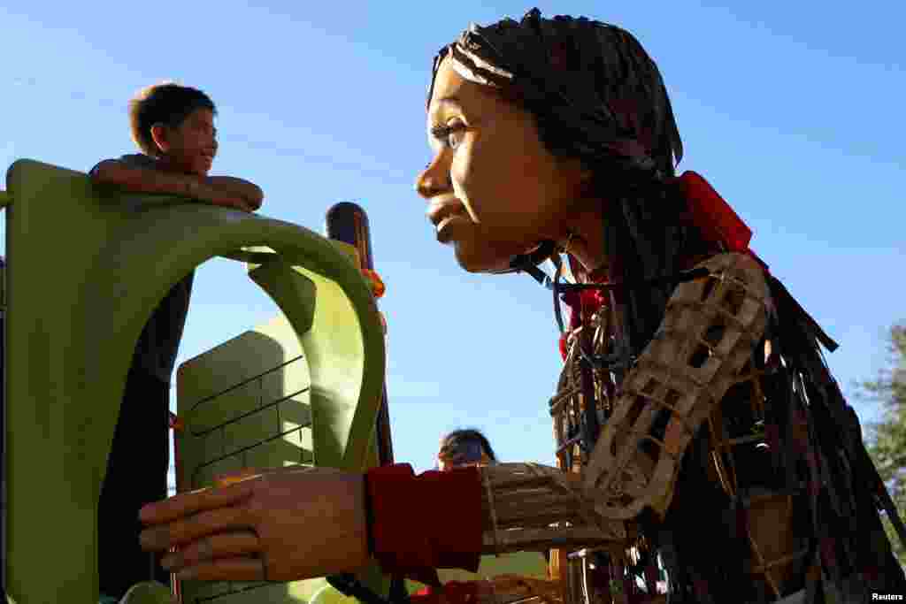 Little Amal, a 12-foot-tall puppet depicting a 10-year-old Syrian refugee, plays with Fabian, a Venezuelan migrant boy, during her journey along the U.S.-Mexico border in El Paso, Texas, Oct. 25, 2023.