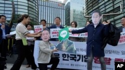 资料照片：韩国首尔的抗议者戴着印有日本首相岸田文雄和韩国总统尹锡悦头像的面罩，手拿着显示Line应用程序的标牌。（2024年5月14日）