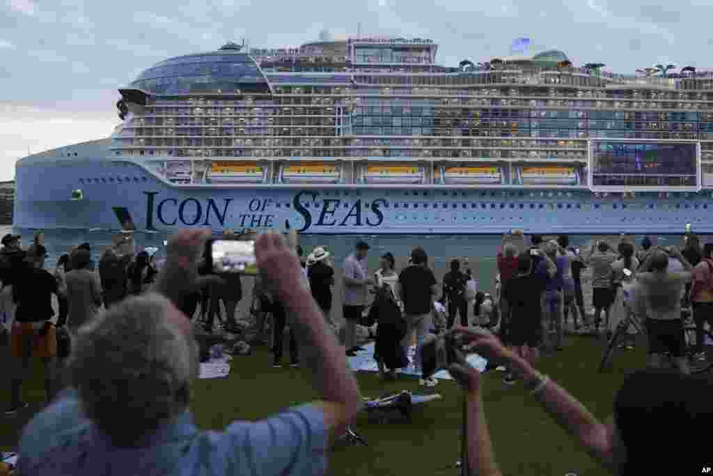 People film from South Pointe Park, as Icon of the Seas, the world's largest cruise ship, sails out of PortMiami on its first public cruise, in Miami Beach, Florida, Jan. 27, 2024.