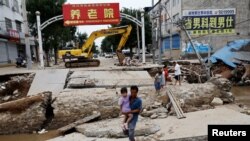 中国河北涿州一名男子抱着女儿试图穿过被洪水冲垮的桥。（2023年8月7日）