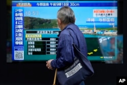台湾强震后，东京一名男子驻足观看日本一家电视台播放对冲绳地区的海啸警报。(2024年4月3日)
