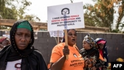 Mwandamanaji anayepinga ukeketaji akishikilia bango nje ya Bunge la Gambia mjini Banjul, Machi 18, 2024. Picha ya AFP