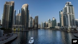 People sit on a boat as it sails along Dubai Marina, United Arab Emirates, Aug. 13, 2024.