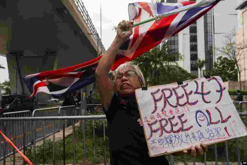 A pro-democracy activist known as "Grandma Wong" protests outside the West Kowloon courts as closing arguments open in Hong Kong's largest national security trial of 47 pro-democracy figures.