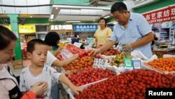 北京一家早市的顾客在挑捡西红柿。（2023年8月9日）