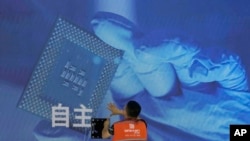 一名工人在上海举办的世界人工智能大会上检查中国科技公司中科曙光展示的芯片和自主字样的屏幕。（2023年7月5日）