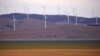 FILE - A fence is seen in front of wind turbines that are part of the Infigen Energy Capital Wind Farm located on the hills surrounding Lake George, near the Australian capital city of Canberra, Australia, Feb. 21, 2018. 