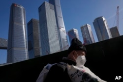 一名打工人扛着他的行李行走在北京商务区。（2023年3月15日）