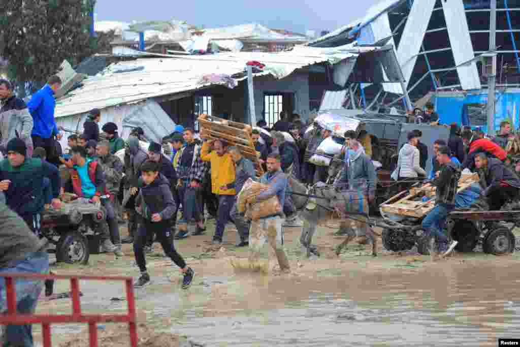Palestinians carry bags of flour they grabbed from an aid truck near an Israeli checkpoint as Gaza residents face crisis levels of hunger, amid the ongoing conflict between Israel and Hamas, in Gaza City, Jan. 27, 2024.