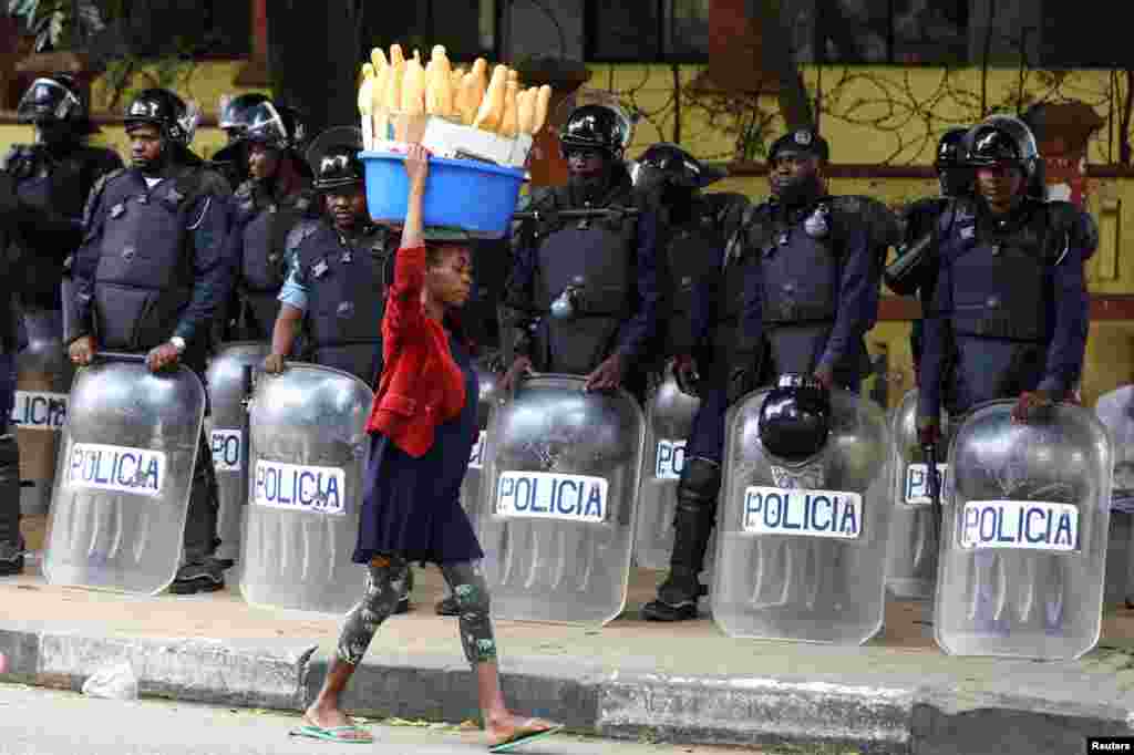 A woman walks past police officers as Angola&#39;s election commission says ruling MPLA party leads with 52% majority, after the general election close in Luanda.