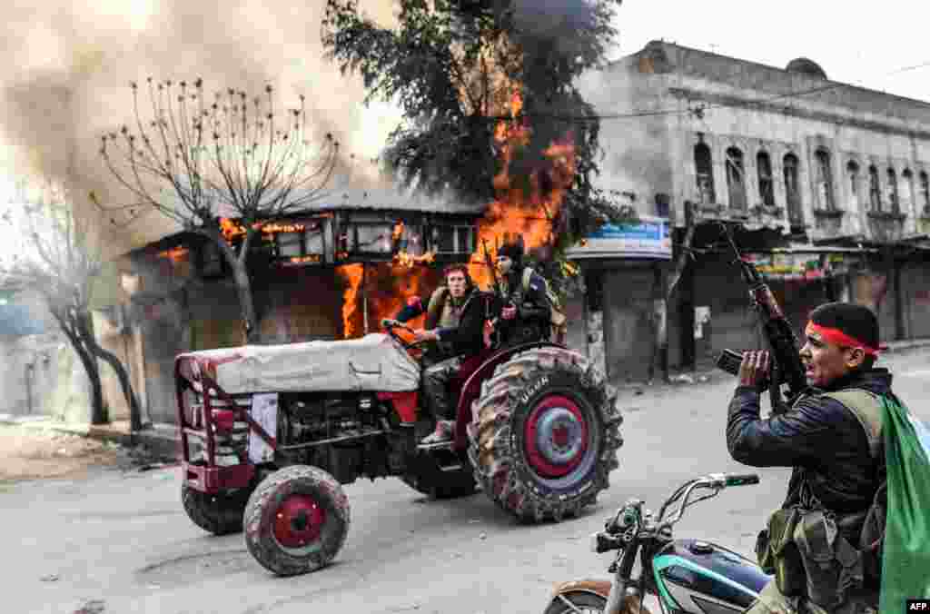 A Turkish-backed Syrian rebel drives past a burning shop in the city of Afrin in northern Syria. Turkish forces and their rebel allies were in control of the Kurdish-majority city of Afrin in northwestern Syria, AFP journalists on the ground reported.