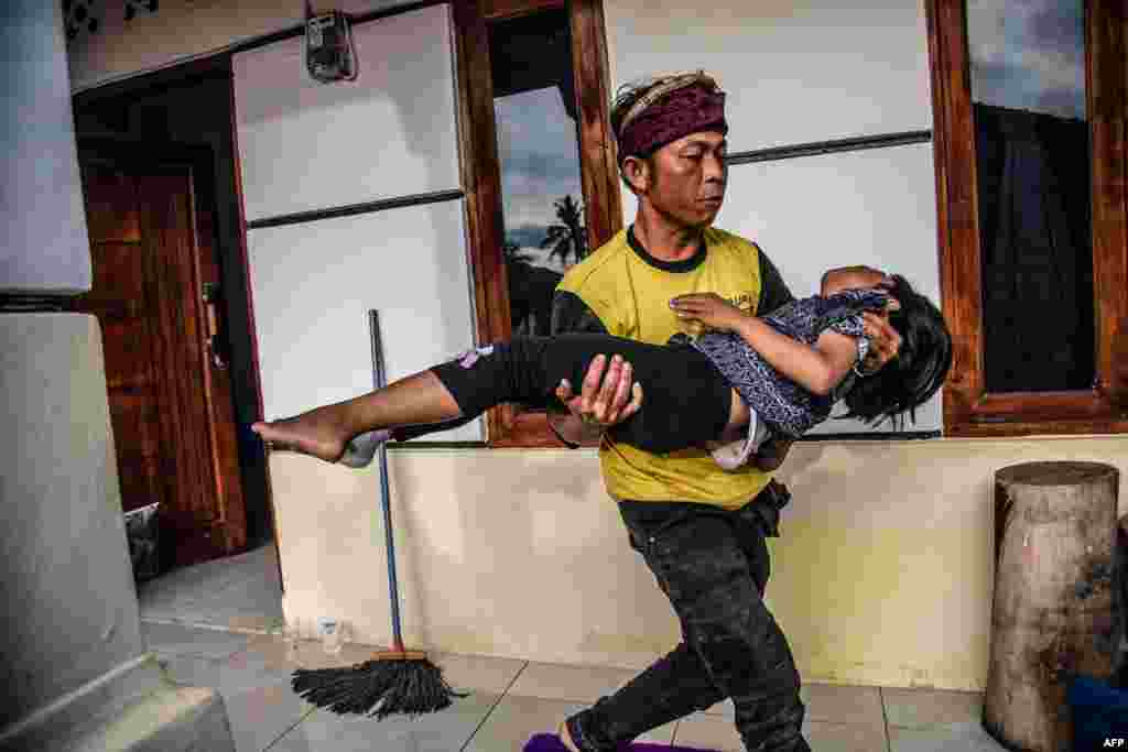 A villager carries his injured daughter following a 5.6-magnitude earthquake that killed at least 162 people, with hundreds injured and others missing in Cianjur, Nov. 22, 2022.