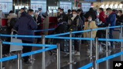 北京国际机场一个国际航班柜台的旅客等候托运行李。（2022年12月29日）