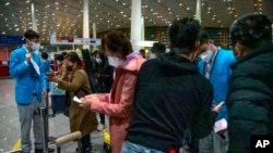 北京国际机场的工作人员在帮助从海外抵达的乘客填写新冠健康状况表格。（2023年1月9日）