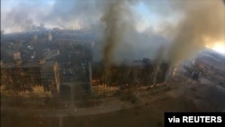 
2022年3月14日，乌克兰马里乌波尔发生爆炸，鸟瞰图显示受损住宅楼冒出浓烟。这张静止图像是从社交媒体获取的无人机镜头中拍摄的。 