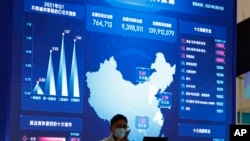 资料照：2021年4月30日，在北京的一个互联网博览会上，一名男子在显示大数据和中国地图的巨型显示器附近用手机说话。（美联社）