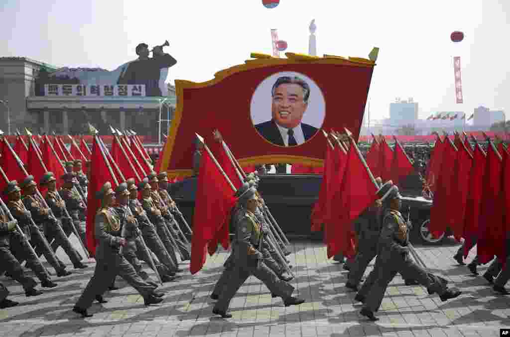 朝鲜军人扛着红旗,在平壤金日成广场簇拥着金日成巨像参加阅兵式(2017年4月15日)。