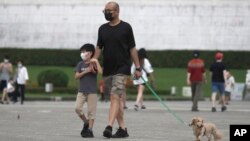 台北市民戴着口罩遛狗散步。（2022年4月27日）