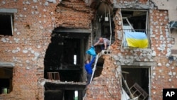 Мешканці виносять свої речі з будинку в Ірпені, який зруйновали російські обстріли, Україна, 21 травня 2022 року.