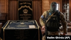 Охоронець заходить до синагоги в єврейському поселенні Анатевка під Києвом, Україна, 27 березня 2022 року. Анатевка була побудована в 2015 році за ініціативою рабина Моше Асмана для євреїв, переміщених через конфлікт на сході України та досі використовується родинами, чиє життя і будинки опинилися у небезпеці через російську агресію. (AP Photo/Vadim Ghirda)