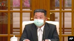 朝鲜领导人金正恩5月12日戴着口罩出席一次会议，承认爆发新冠病毒疫情。（电视画面截图）