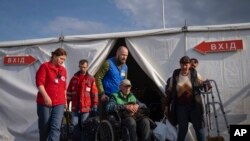 Волонтери допомагають чоловікові після його прибуття з українського міста Маріуполь у центрі для переміщених осіб у Запоріжжі, Україна, 3 травня 2022 року. (AP Photo/Євген Малолетка).
