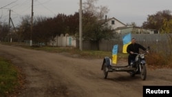 Учитель Юрій Невольчук їде на мотоциклі з українськими прапорами в селі Благодатне, відвойованому ЗСУ на Херсонщині, 11 листопада 2022 року. REUTERS/Валентин Огіренко