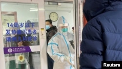 2022年12月15日，一名男子在北京一家医院的发热门诊门外排队等待。一位身着防护服的医务人员正准备关门。中国有关当局毫无预兆地宣布解封后，新冠肺炎的感染人数和死亡人数不断增加，引起人们的恐慌。
