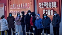 北京市民在宣传习近平思想的标语墙前排队等候接受核酸检测。（2022年12月5日）