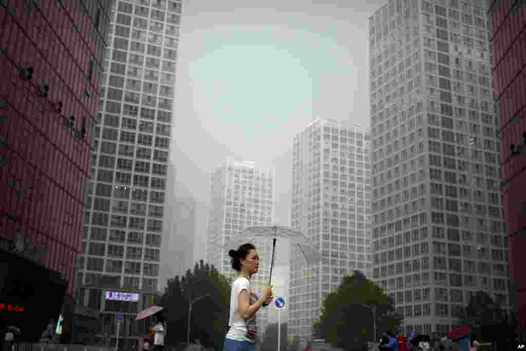 2017年8月11日，她在雨中穿过北京中央商务区。虽然中国的首都处于半干旱的气候，但在夏季几乎每年都有大量降水