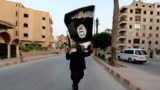 ISIS အကြမ်းဖက်အဖွဲ့ဝင်နဲ့ IS အလံ (REUTERS/Stringer)