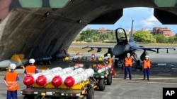 资料图片：台湾军队士兵站在F16V战机前，准备进行装载美制AGM-84鱼叉反舰导弹及AIM-120和AIM-9空空导弹的训练。（2022年9月16日）