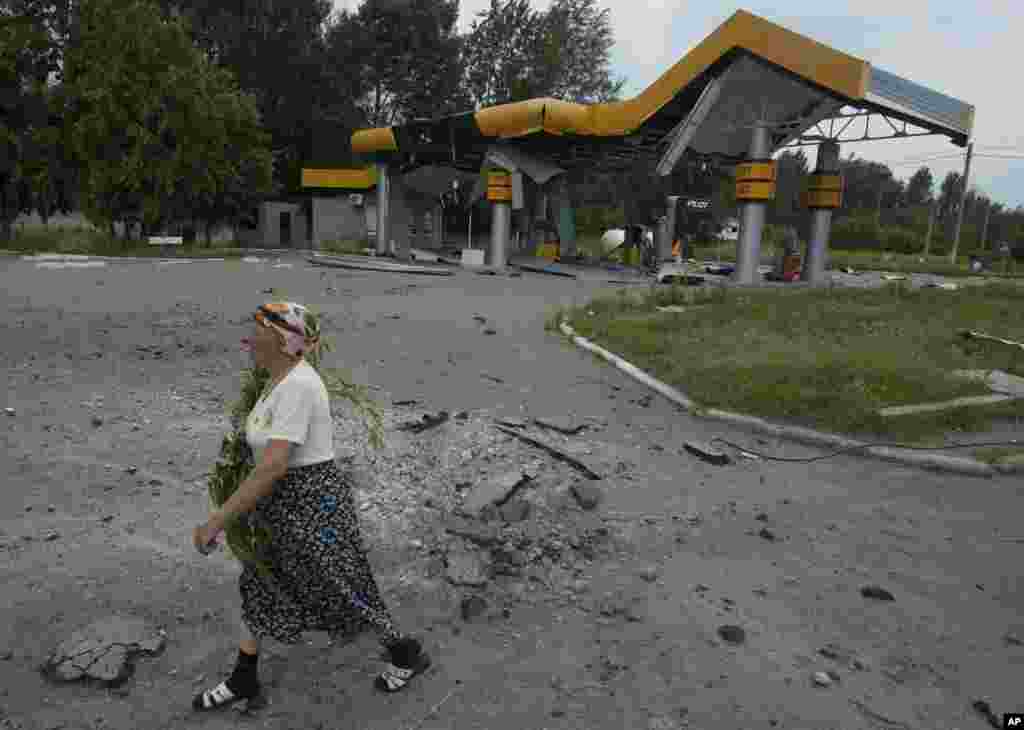 Жінка іде повз розбиту артилерією заправку. Слов'янськ.
