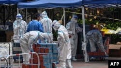 身穿防护服的工作人员正在检查即将配送给静安区小区居民的食品是否遭受病毒的污染。2022年4月10日。