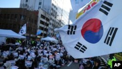 2024 年 12 月 15 日，韩国首尔，参加者举着标语呼吁宪法法院罢免总统尹锡烈。标语上写着“立即逮捕”。
