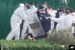 中国河南郑州富士康代工厂里身穿防护服的警察和保安殴打参加示威活动的工人。(2022年11月23日)