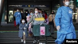 身穿防护服的韩国军人引领一组从中国飞抵仁川国际机场的旅客。（2023年1月12日）