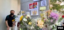英国驻港总领事馆大楼的支柱上贴满悼念女皇的鲜花和心意卡，有手持鲜花排队等候进入领事馆签署吊唁册的市民神情哀伤 (美国之音/汤慧云)