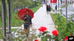9月14日，一场降雨之后，人们在朝鲜首都平壤中心地区走路。