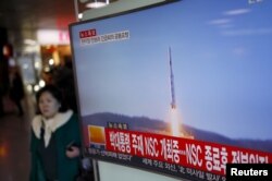 2016年２月７日，韩国首尔火车站，一位旅客走过正在显示北朝鲜发射远程火箭新闻的电视屏幕。