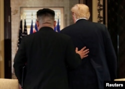 金正恩伸手抚住川普的背