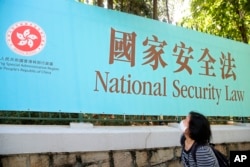 香港一名妇女走过街头的国安法宣传牌。（2020年6月30日）