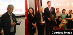左图：重病康复中的“中国法律界良知”张思之致颁奖辞。右图：2014年度公和人物颁奖典礼会主持人耿潇男女士（左一）与她称为“圣徒”而鼎力推荐的卢百可先生，与张思之先生（左二）共同为卢百可颁奖。（左三）卢百可带他的四个女儿与颁奖人在颁奖台合影，手持木刻画像由独立学人毛喻源雕刻（耿潇男拍摄）