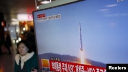 2016年２月７日，韩国首尔火车站，一位旅客走过正在显示北朝鲜发射远程火箭新闻的电视屏幕。